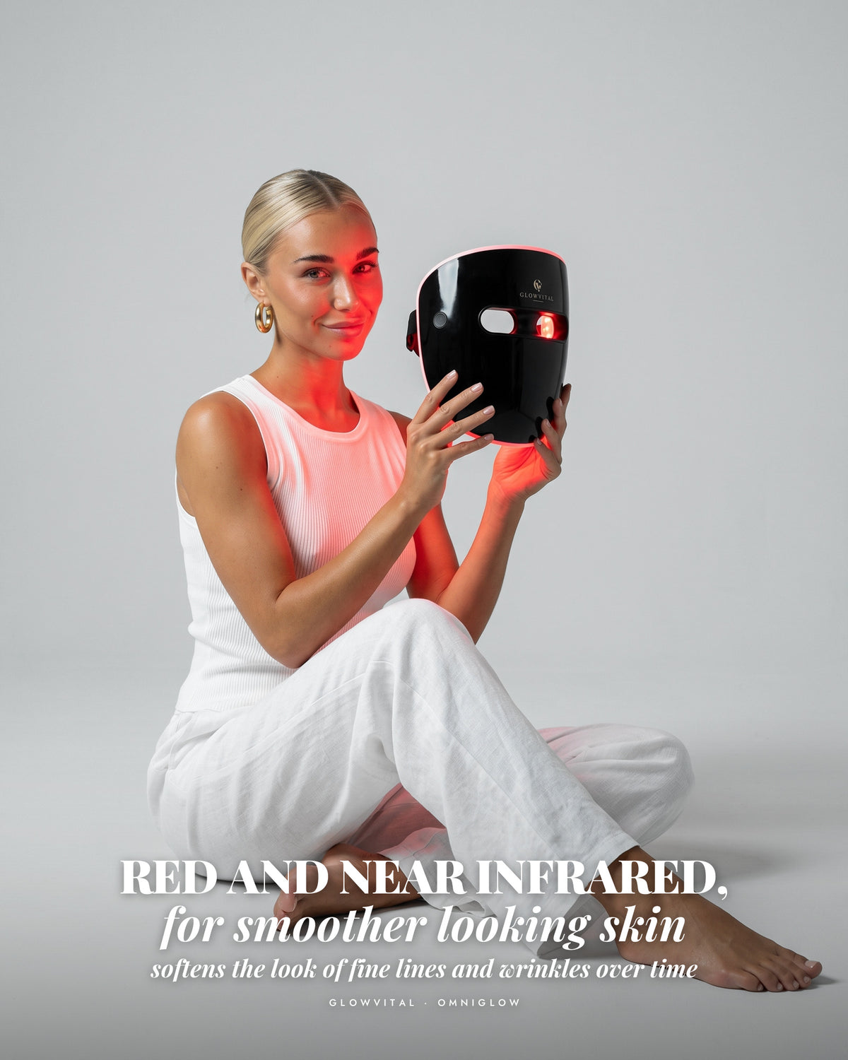 Woman holding the OmniGlow mask glowing red
